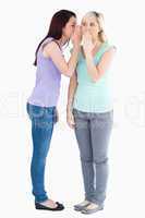 Cute woman telling friend a secret