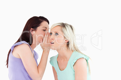 Portrait of a cute woman telling her friend a secret