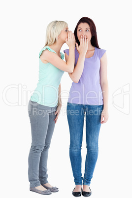 Blond woman telling her friend a secret