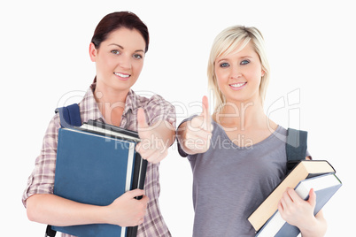 Female students with books and thumbs up