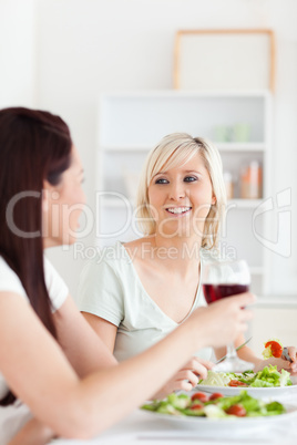 Portrait of joyful Women eating salad and drinking wine