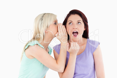 Portrait of a blond woman telling her friend a secret