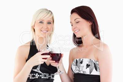 Charming well-dressed women toasting with red wine