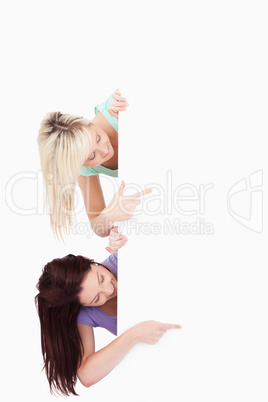 Charming Women peeking around a banner showing copyspace