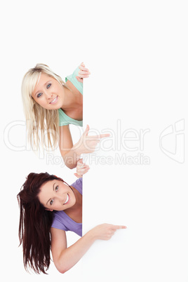 Cute Women peeking around a banner showing copyspace