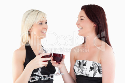 Laughing well-dressed women toasting with red wine