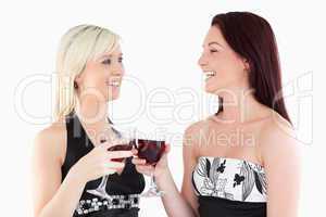 Laughing well-dressed women toasting with red wine