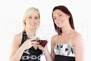 Joyful well-dressed women toasting with red wine