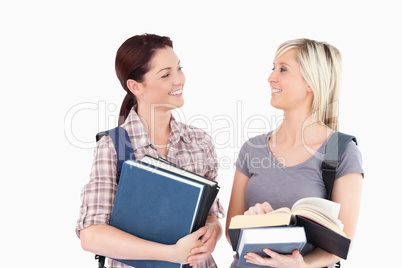 Students with books looking at each other