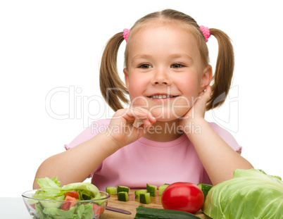 Little girl is cutting carrot for salad