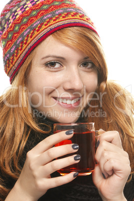 rothaarige junge frau in winterkleidung hält ein glas tee in den händen
