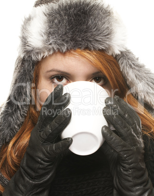 junge rothaarige frau in winterkleidung trinkt aus einer weissen tasse