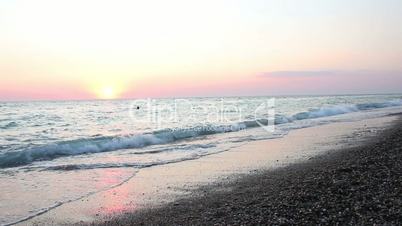 Woman walks on the beach at sunset