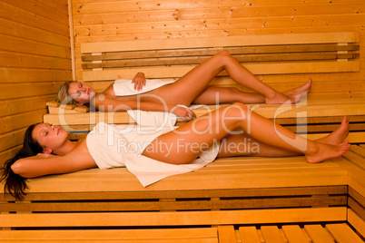 Sauna two women relaxing lying wrapped towel