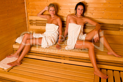 Sauna two women relaxing sitting wrapped towel
