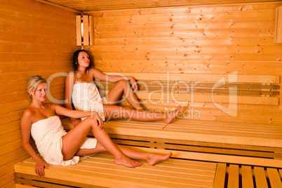 Sauna two women relaxing sitting wrapped towel