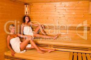 Sauna two women relaxing sitting wrapped towel