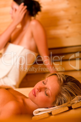Sauna two women relaxing sweating covered towel