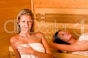 Sauna two women relaxing sweating covered towel