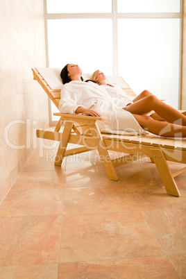 Beauty spa room two women relax sun-beds
