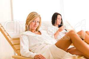 Luxury spa two women relax sitting sun-beds