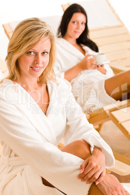 Luxury spa two women relax sitting sun-beds