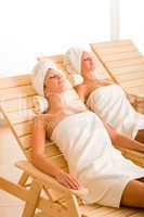 Beauty spa room two women relax sun-beds