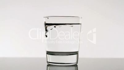 Black Ink Dropping Into Water Glass