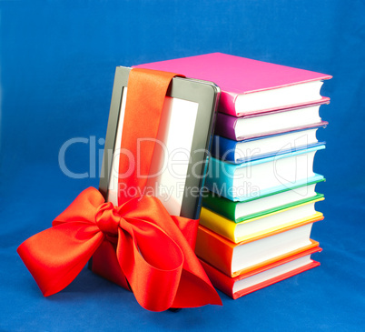 Electronic book reader tied up with red ribbon and stack of books