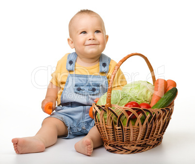 Cute little boy with basket full of vegetables