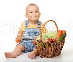 Cute little boy with basket full of vegetables