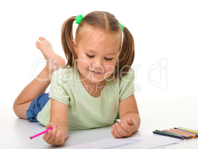 Little girl is drawing while laying on the floor