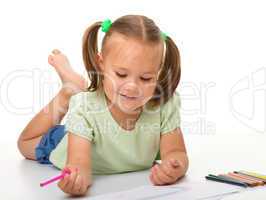 Little girl is drawing while laying on the floor