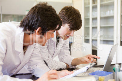 Male chemistry students writing a report