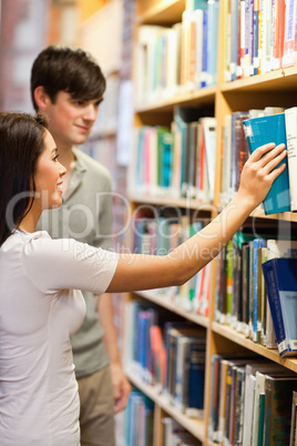 Portrait of students choosing a book on a shelf