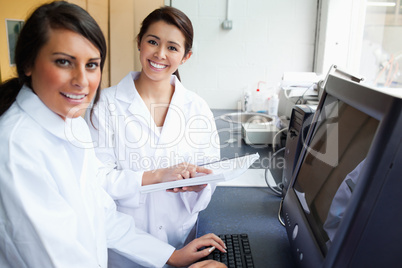 Smiling scientists posing with a monitor