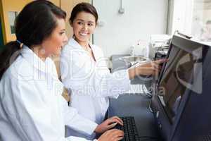 Smiling female scientists working with a monitor