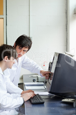 Phisician pointing at something on a monitor to his student