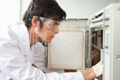 Close up of a scientist using a laboratory chamber furnace