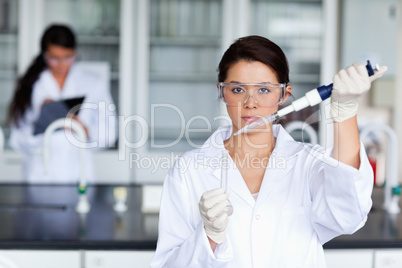 Serious female scientist pouring a liquid in a tube