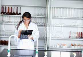 Serious female scientist writing on a clipboard