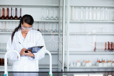 Focused female scientist writing on a clipboard