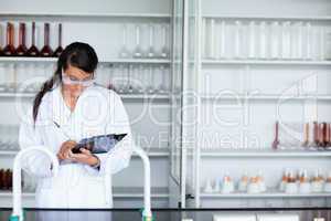 Focused female scientist writing on a clipboard