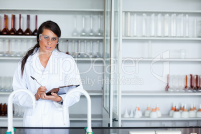Cute female scientist writing on a clipboard