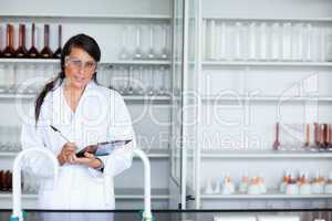 Cute female scientist writing on a clipboard