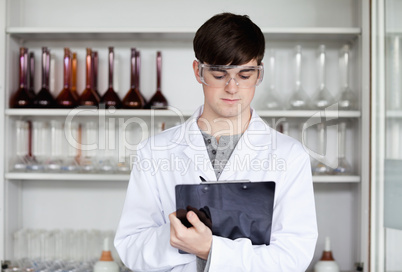 Male scientist writing on a clipboard