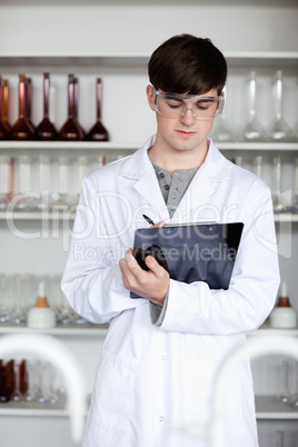 Portrait of a male scientist writing on a clipboard