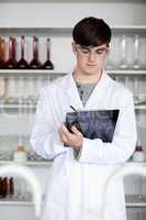 Portrait of a male scientist writing on a clipboard