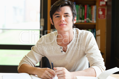 Smiling male student writing an essay