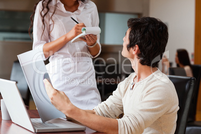 Young man ordering food to a waitress